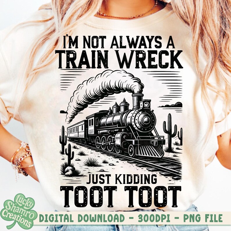K&ouml;nnte beinhalten: Cremefarbenes T-Shirt mit einer Schwarz-Wei&szlig;-Illustration einer alten Dampflokomotive und dem Text "I'M NOT ALWAYS A TRAIN WRECK JUST KIDDING TOOT TOOT". Das Design umfasst Kakteen und eine W&uuml;stenlandschaft.