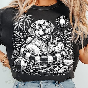 May include: Black graphic t-shirt featuring a dog wearing sunglasses and floating in a pool on an inner tube. The dog is holding a drink with a straw. Palm trees, a sun, and beach accessories complete the summer scene.