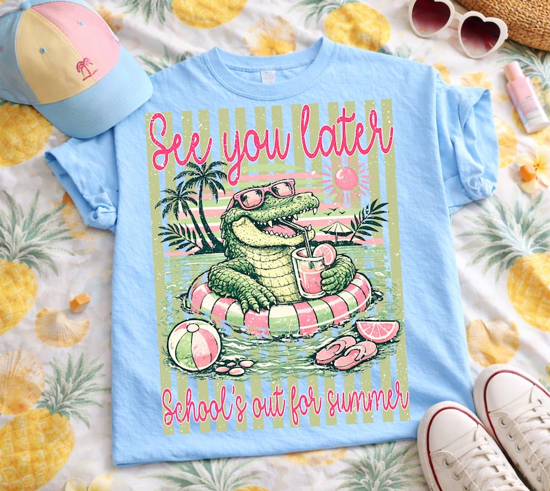 May include: Pale blue t-shirt featuring a cartoon alligator wearing sunglasses and drinking a beverage while floating on an inflatable ring. The text "See you later" and "School's out for summer" are also on the shirt. A matching baseball cap is visible.