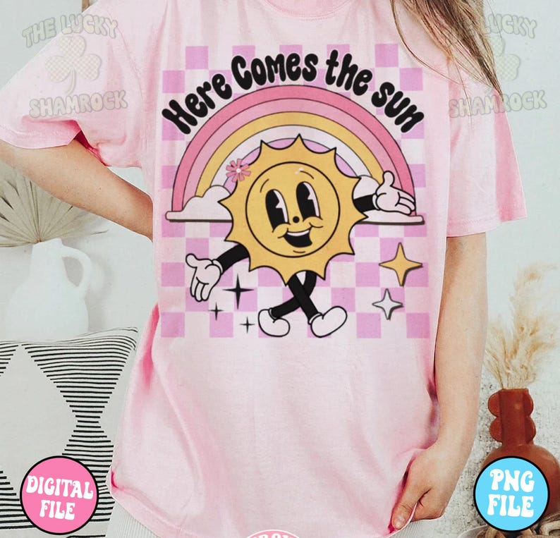 May include: Pink t-shirt with a graphic of a smiling sun with a rainbow and the text "Here Comes the Sun".
