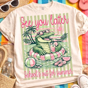 K&ouml;nnte beinhalten: Cremefarbenes T-Shirt mit einem Cartoon-Alligator mit Sonnenbrille auf einem Schwimmring. Der Aufdruck zeigt die Schriftz&uuml;ge "See you later" und "School's out for summer" in Rosa, passend zum Sommer.