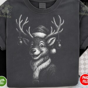 May include: Dark gray t-shirt featuring a detailed black and white illustration of a reindeer wearing a Santa hat and scarf. The reindeer has large antlers with ornaments hanging from them. The text "THE LUCKY SHAMROCK" is printed on the upper left sleeve.