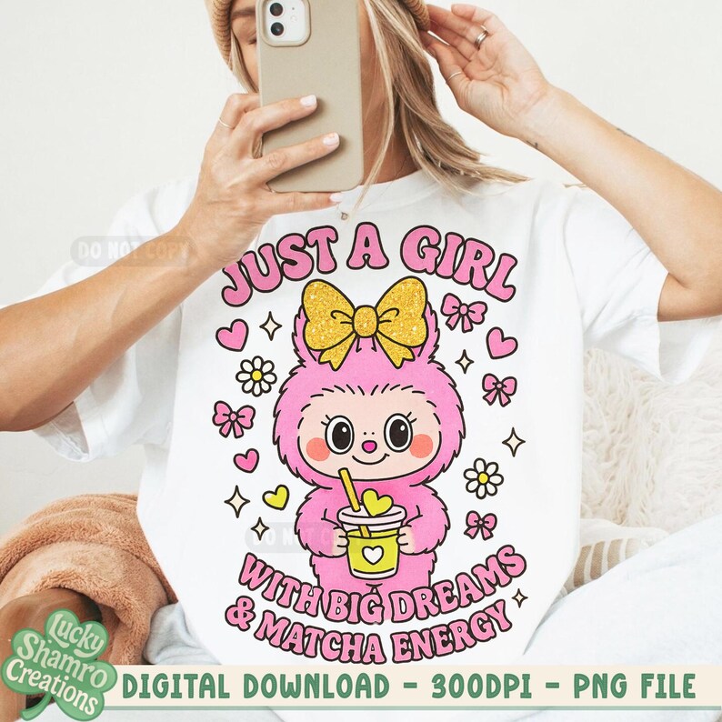 May include: White t-shirt featuring a cartoon character with a pink body, a yellow bow, and a drink. The text "JUST A GIRL WITH BIG DREAMS & MATCHA ENERGY" is displayed in pink. Additional graphics include hearts, flowers, and bows. Digital download.