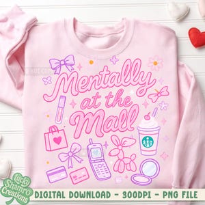 May include: Pink sweatshirt with the phrase "Mentally at the Mall" in a whimsical font. The design includes illustrations of a shopping bag, a cell phone, a balloon animal, a makeup compact, and a coffee cup.