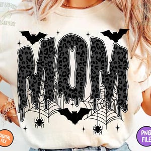 May include: Cream-colored t-shirt featuring the word "MOM" in a dripping, leopard-print design. The design includes bats, spiderwebs, and spiders, with the text "DIGITAL FILE" and "PNG FILE" in the corners. A Halloween-themed graphic.