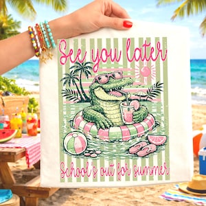 K&ouml;nnte beinhalten: Wei&szlig;e Tragetasche mit farbenfrohem Sommerdesign. Das Design zeigt ein Cartoon-Alligator mit Sonnenbrille, der ein Getr&auml;nk trinkt, w&auml;hrend er in einem Pool schwimmt. Der Text lautet "See you later" und "School's out for summer".