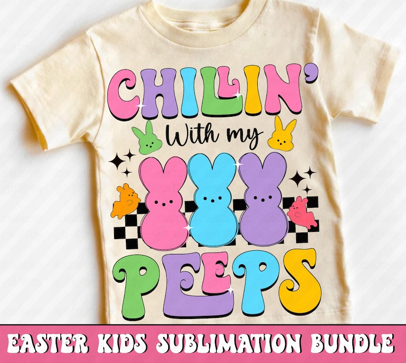 Puede incluir: Una camiseta crema para ni&ntilde;os con la frase "CHILLIN' With my PEEPS" en letras coloridas. El dise&ntilde;o incluye conejitos de dibujos animados y un patr&oacute;n de tablero de ajedrez, ideal para Pascua.