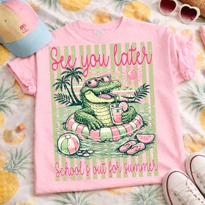 K&ouml;nnte beinhalten: Rosa T-Shirt mit einem Aufdruck eines Alligators mit Sonnenbrille, der mit einem Getr&auml;nk in einem Pool schwimmt. Der Text "See you later" und "School's out for summer" ist auf dem Shirt aufgedruckt. Ein Strandball, Flip-Flops und ein Hut sind ebenfalls zu sehen.