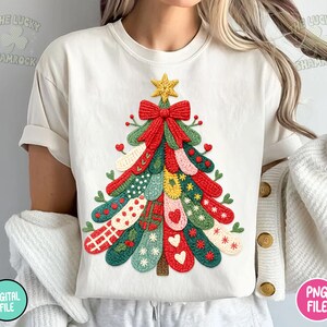 May include: Cream-colored t-shirt featuring a colorful Christmas tree design. The tree is composed of various patterned elements in red, green, yellow, and white, topped with a gold star and a red bow. The text "THE LUCKY SHAMROCK" is visible.