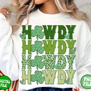 May include: White sweatshirt with a green, white, and brown graphic design that says "Howdy" four times. The graphic design features shamrock and leopard print patterns.