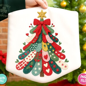 May include: A white Christmas tree-shaped banner with a colorful, textured design. The tree features a red bow, a gold star, and various patterned sections in red, green, and white. The banner is held up by a hand.