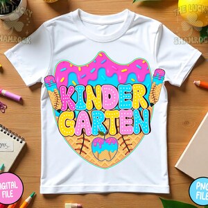 May include: White t-shirt with a colorful "Kindergarten" graphic. The design features a donut, ice cream cones, and an apple, all in vibrant pink, blue, and yellow hues. The shirt is a playful design for young children.