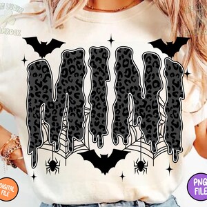 May include: Cream-colored t-shirt with a Halloween-themed design. The word "MINI" is displayed in a dripping font with a leopard print pattern. Bats, spiderwebs, and spiders surround the word, with star accents.