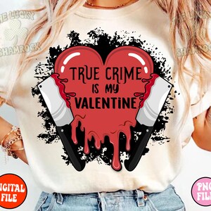 May include: White t-shirt with a red heart graphic that says "True Crime is my Valentine". The heart is dripping with red and there are two black knives on either side of the heart.