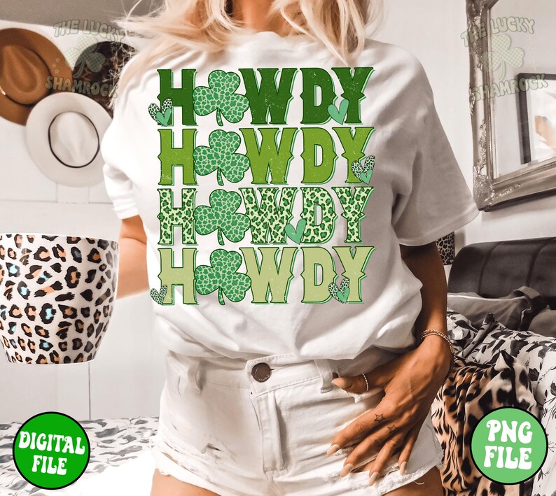 May include: White t-shirt with the text "Howdy" repeated four times in green, yellow, and leopard print. Each "Howdy" is decorated with a green shamrock.
