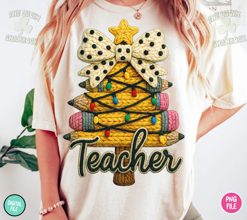 May include: Cream-colored t-shirt featuring a Christmas tree design made of pencils. The tree is adorned with a bow, star, and colorful lights. The word "Teacher" is written in a decorative font at the bottom of the tree.