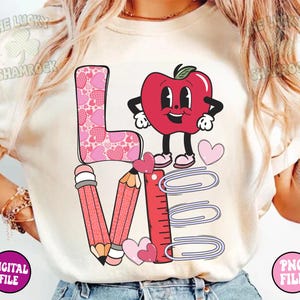 May include: A white t-shirt with a pink, red, and purple graphic design that says "LOVE" with a red apple character and school supplies.