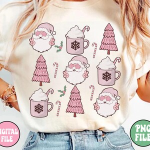 K&ouml;nnte beinhalten: Ein wei&szlig;es T-Shirt mit einem rosa-wei&szlig;en Weihnachtsmotiv. Das Design zeigt den Weihnachtsmann, Weihnachtsb&auml;ume, Zuckerstangen und hei&szlig;e Schokolade. Der Text "DIGITAL FILE" befindet sich in der linken unteren Ecke und "PNG FILE" in der rechten unteren Ecke.