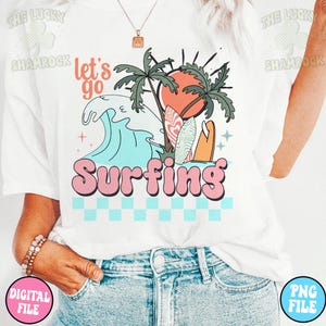 May include: White t-shirt with a graphic design of a wave, palm trees, a sunset, and surfboards. The text "Let's go Surfing" is in pink letters.