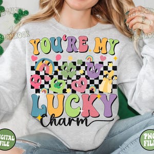 Peut inclure: Un sweat-shirt gris avec le texte "You're My Lucky Charm" en couleurs arc-en-ciel. Le texte est entour&eacute; d'un motif &agrave; carreaux et de personnages de dessins anim&eacute;s aux couleurs arc-en-ciel.