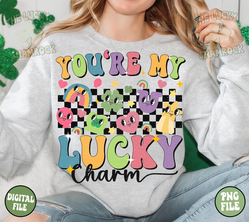 Peut inclure: Un sweat-shirt gris avec le texte "You're My Lucky Charm" en couleurs arc-en-ciel. Le texte est entour&eacute; d'un motif &agrave; carreaux et de personnages de dessins anim&eacute;s aux couleurs arc-en-ciel.