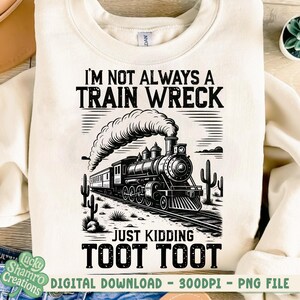 K&ouml;nnte beinhalten: Cremefarbenes Sweatshirt mit einer schwarz-wei&szlig;en Grafik einer alten Dampflok. Der Text lautet: "I'M NOT ALWAYS A TRAIN WRECK JUST KIDDING TOOT TOOT". Das Design umfasst Kakteen und Bahngleise.