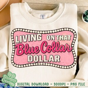 May include: Cream-colored sweatshirt with the text "LIVING ON THAT Blue Collar DOLLAR" in a pink and white design. The graphic is framed by a dotted border. The sweatshirt is a digital download.