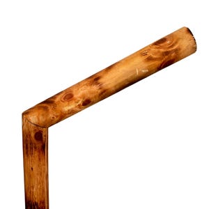 May include: A wooden stick bent at a 90-degree angle, with a natural brown finish. The stick is tied with a brown rope at the bottom.