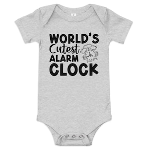 May include: A grey baby onesie with black text that reads "World's Cutest Alarm Clock" and a black and white illustration of an alarm clock.