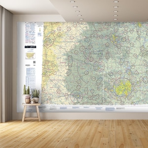 May include: A detailed aerial map of a region with numerous circles and lines, printed on a white background. The map is mounted on a wall in a room with a wooden floor and a window.