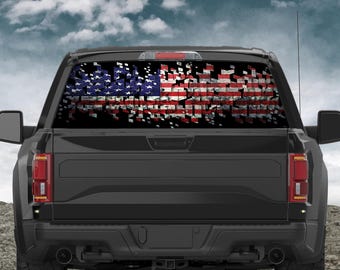 May include: A black pickup truck with a rear window graphic of a distressed American flag. The flag design features red and white stripes and blue stars, with a fragmented, pixelated effect.