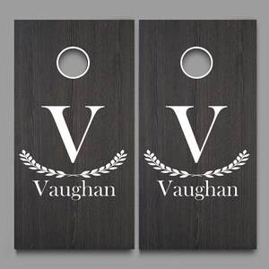 May include: Two wooden cornhole boards with a white wreath and the letter V and the name Vaughan on each board.