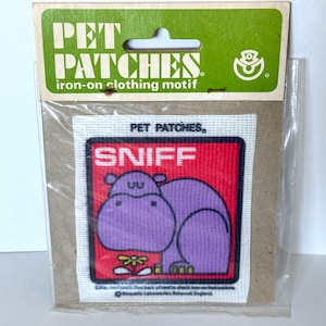 May include: Iron-on patch featuring a purple hippopotamus with the text "SNIFF" in a red box. The patch is labeled "PET PATCHES" and is intended for clothing.
