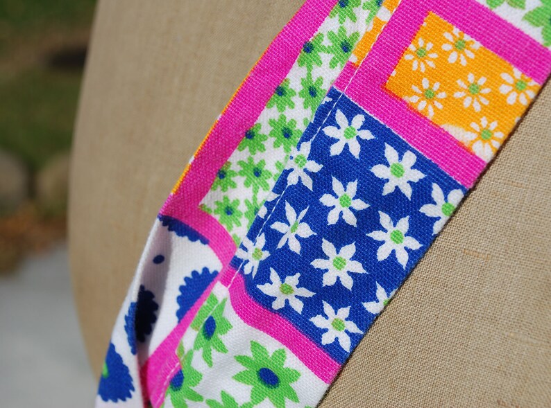 Puede incluir: Primer plano de una tela colorida con un patr&oacute;n floral. La tela es rosa, azul, verde y amarilla. Las flores son blancas con centros verdes.