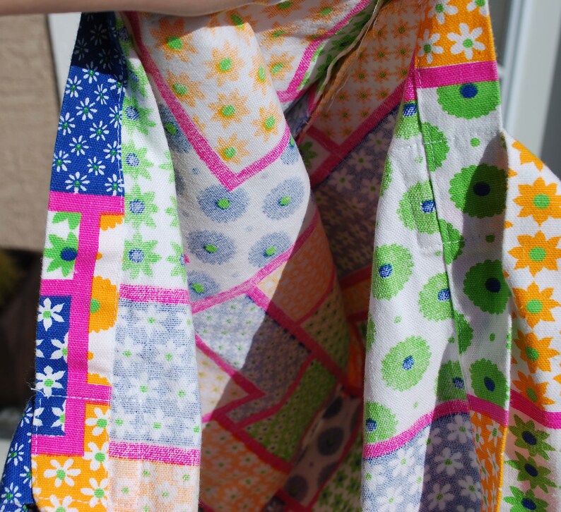 Puede incluir: Una tela de patchwork colorida con una variedad de patrones florales en tonos de rosa, azul, verde y blanco. La tela est&aacute; doblada por la mitad, revelando el reverso, que es blanco s&oacute;lido con acentos florales verdes y azules.
