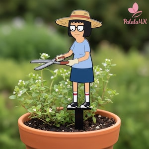 May include: A decorative garden stake featuring a cartoon character with black hair, glasses, and a straw hat, wearing a light blue shirt and dark blue skirt. The character holds metal garden shears and stands on a black base in a plant pot.