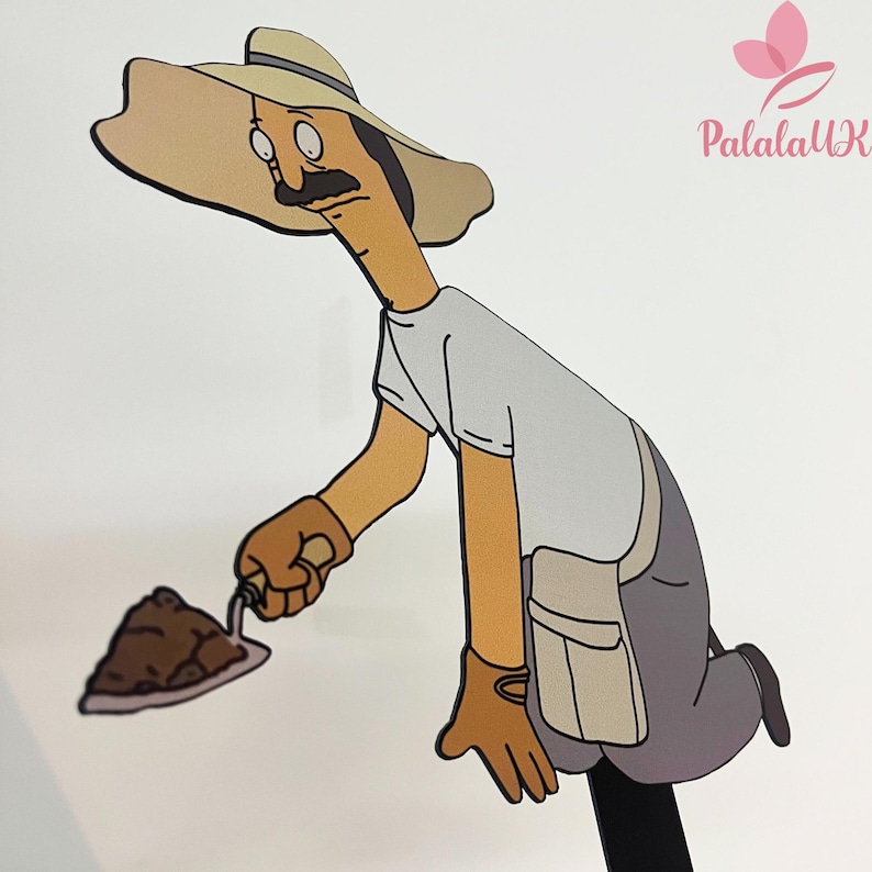 May include: A flat, cartoon-style cutout of a character with a tan complexion, a dark mustache, and round glasses. The figure wears a wide-brimmed tan hat, a light gray t-shirt, and gray pants, holding a small metal trowel with a pile of brown soil.