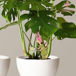 May include: A large green monstera plant in a white ceramic pot. A cartoon character wearing a pink bunny ear hat and a green dress is positioned among the stems, holding a pair of silver garden shears to trim a leaf of the plant.
