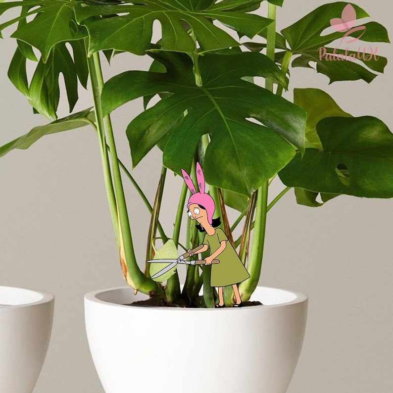 May include: A large green monstera plant in a white ceramic pot. A cartoon character wearing a pink bunny ear hat and a green dress is positioned among the stems, holding a pair of silver garden shears to trim a leaf of the plant.