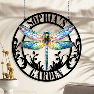 May include: Black metal garden sign with a dragonfly design and the text "Sophia's Garden". The dragonfly has colorful wings with a stained glass effect.