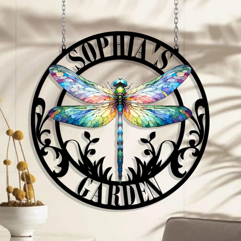 May include: Black metal garden sign with a dragonfly design and the text "Sophia's Garden". The dragonfly has colorful wings with a stained glass effect.