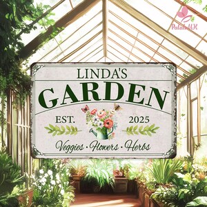 Pode incluir: Uma placa de metal retangular com o texto "LINDA'S GARDEN" em verde. A placa inclui as palavras "Est. 2025" e "Veggies • Flowers • Herbs". Uma ilustração floral com borboletas e um regador está no centro.
