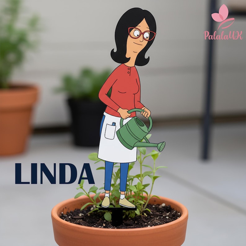 May include: A flat, decorative plant stake featuring a cartoon character with black hair, red glasses, a red long-sleeved shirt, and a white apron, holding a green watering can. The word LINDA is printed in bold, dark blue capital letters below.