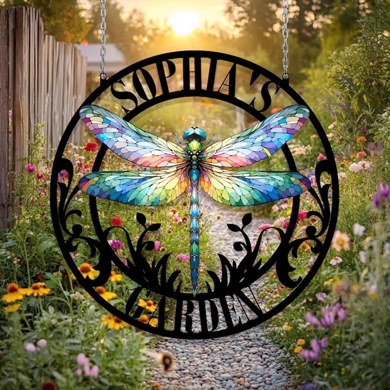 May include: A black metal garden sign with a dragonfly design and the text "Sophia's Garden". The dragonfly is made of stained glass with colorful wings.