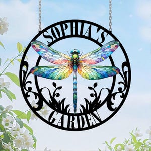 May include: A black metal garden sign with a dragonfly design and the text "Sophia's Garden". The dragonfly has colorful wings with a stained glass effect.