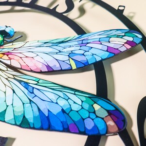 May include: A colorful dragonfly with blue, green, purple, and pink wings. The dragonfly is a metal wall decor piece.
