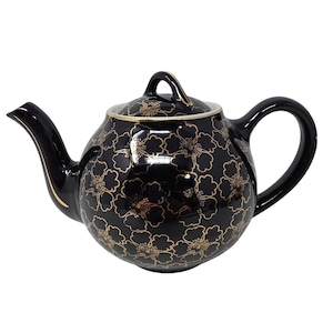 May include: A glossy black ceramic teapot featuring a repeating gold floral pattern across its rounded body and lid. The teapot includes a curved spout, a sturdy handle, and a matching lid with a small handle, all accented with gold trim.