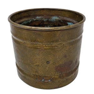 May include: A weathered, cylindrical brass planter with a slightly flared rim. The planter has horizontal bands and a textured surface, showing signs of age and oxidation. The interior has a greenish-blue patina.