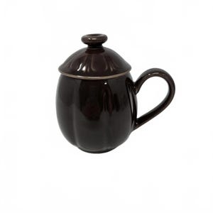 May include: A dark brown ceramic mug with a matching lid. The mug has a rounded body with vertical ridges and a curved handle. The lid has a small knob on top. The mug is designed for hot beverages.