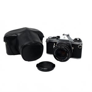 May include: A vintage Pentax camera with a black and silver body, lens cap, and a black leather case. The lens is marked "PENTAX-M 1:1.7 50mm". The camera is a classic photography item.